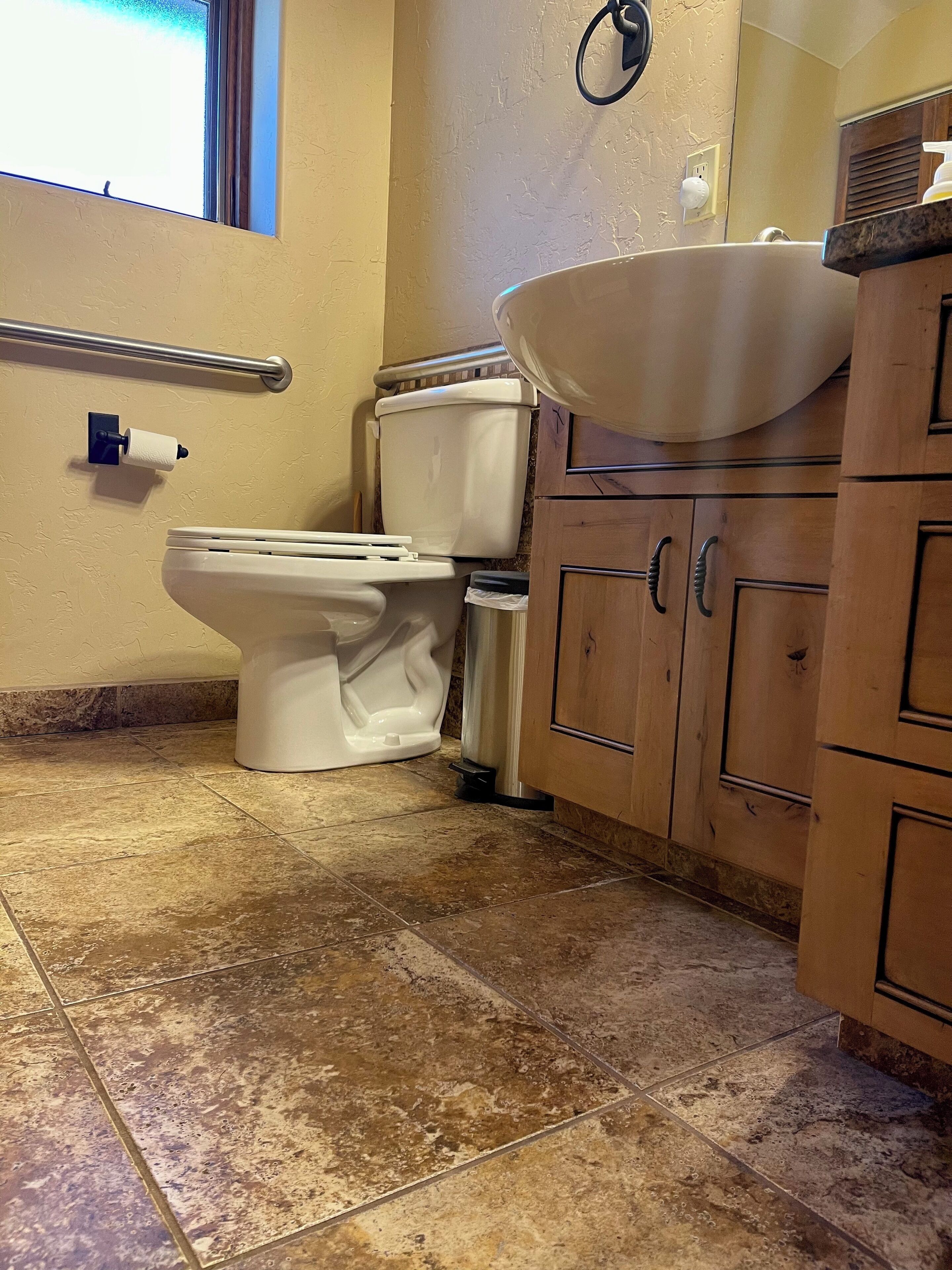 A bathroom with a toilet, a sink, and wooden cabinets.