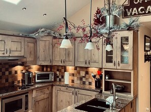 Una cocina con armarios de madera, microondas, tostadora y lavamanos.