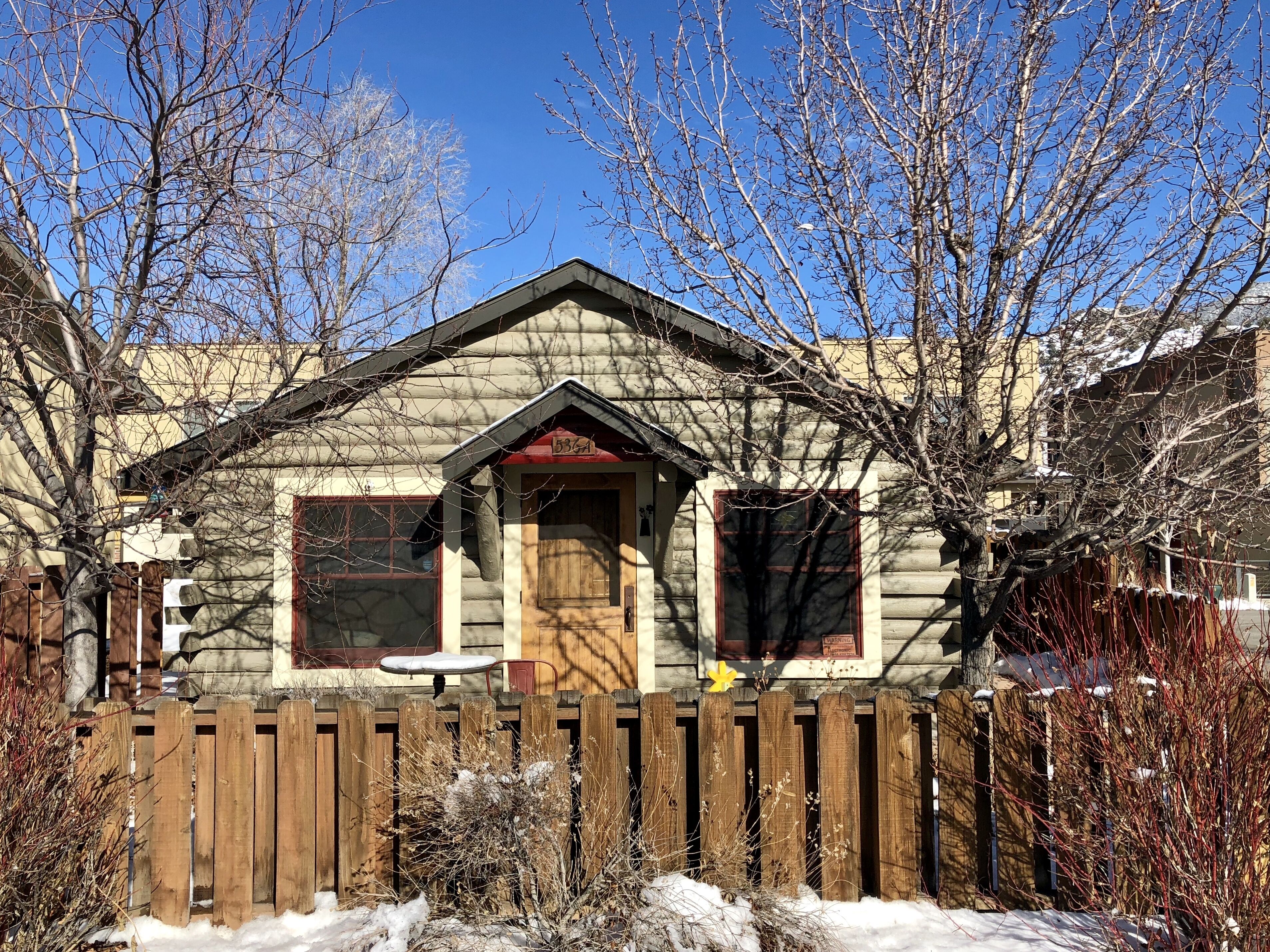 A log cabin with a wooden door, two windows, and a small porch.