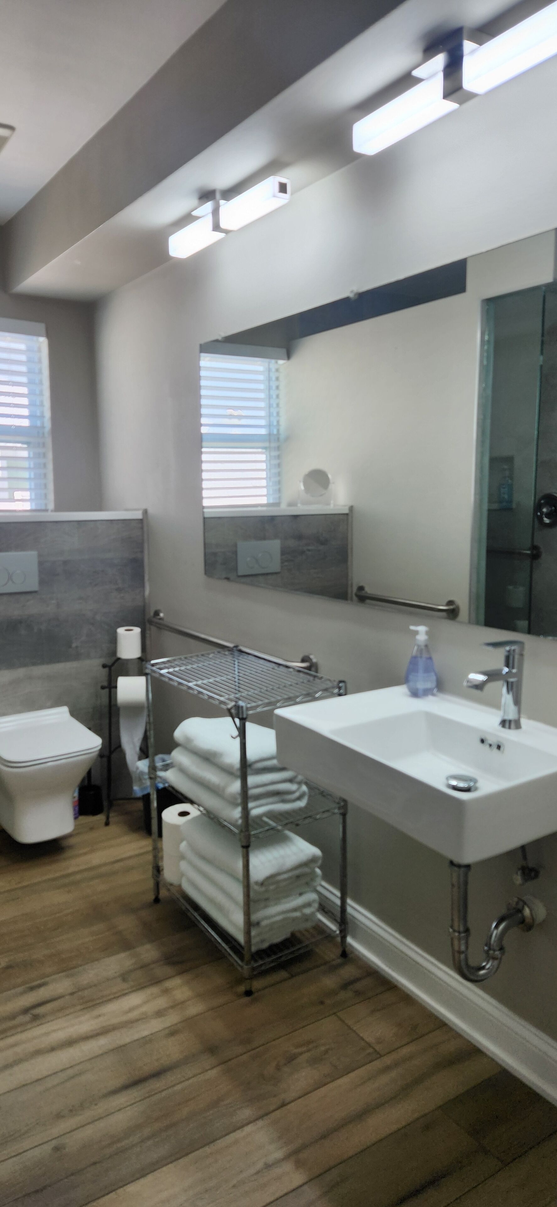A modern bathroom with a white sink, a mirror, and a toilet.