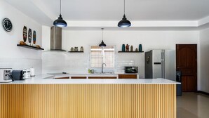 A modern kitchen with a central island, pendant lights, and a large window.