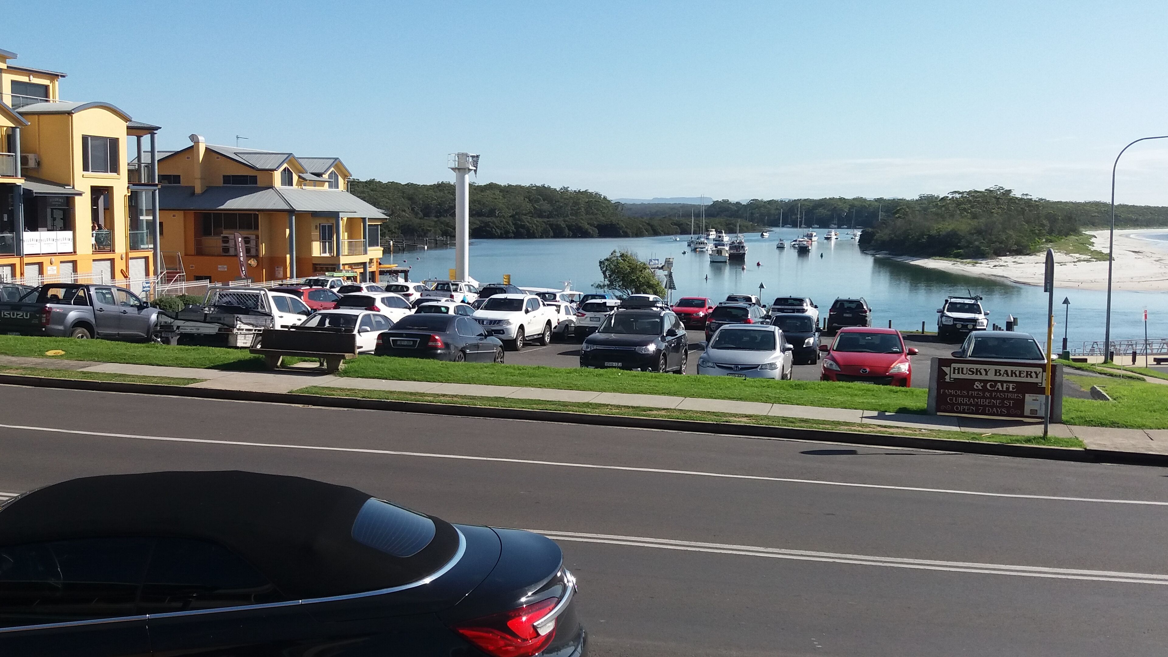A parking lot with cars and a building with a sign for Husky Bakery & Cafe.