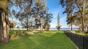 A grassy park area with trees and a view of a lake. - Absolute Waterfront - large deck, level access to water, plenty wildlife (St Georges Basin)