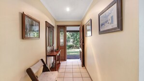A hallway with a bench, framed pictures on the walls, and a door leading outside. - Absolute Waterfront - large deck, level access to water, plenty wildlife (St Georges Basin)