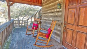 Une véranda en bois avec deux fauteuils à bascule et une porte en bois.
