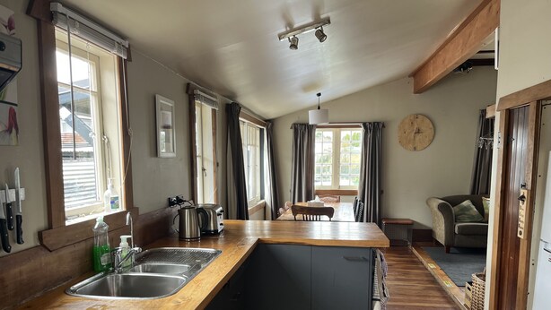 A kitchen with a wooden countertop, a sink, and a dining area with a table and chairs. - Piwari Villa  - Summer Hike & Bike, Winter Snow & Spa  (Rangataua)