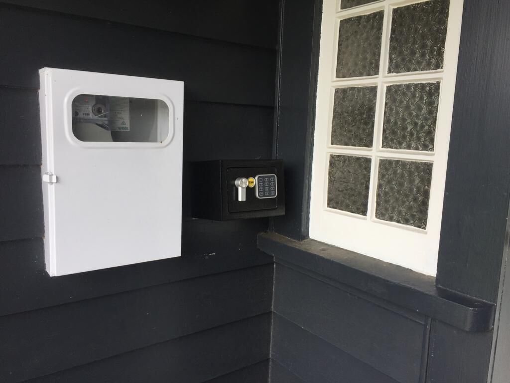 A white door with a window, a black safe, and a window with frosted glass panes.