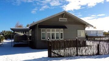 A single-story house with a sloped roof, a covered porch, and a fenced yard.