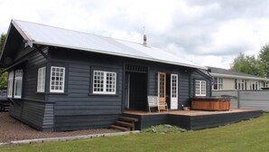 A black wooden building with a metal roof, a wooden door, and a bench outside. - Piwari Villa  - Summer Hike & Bike, Winter Snow & Spa  (Rangataua)