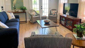 A living room with a sofa, two rocking chairs, a coffee table, a TV, and a bookshelf.