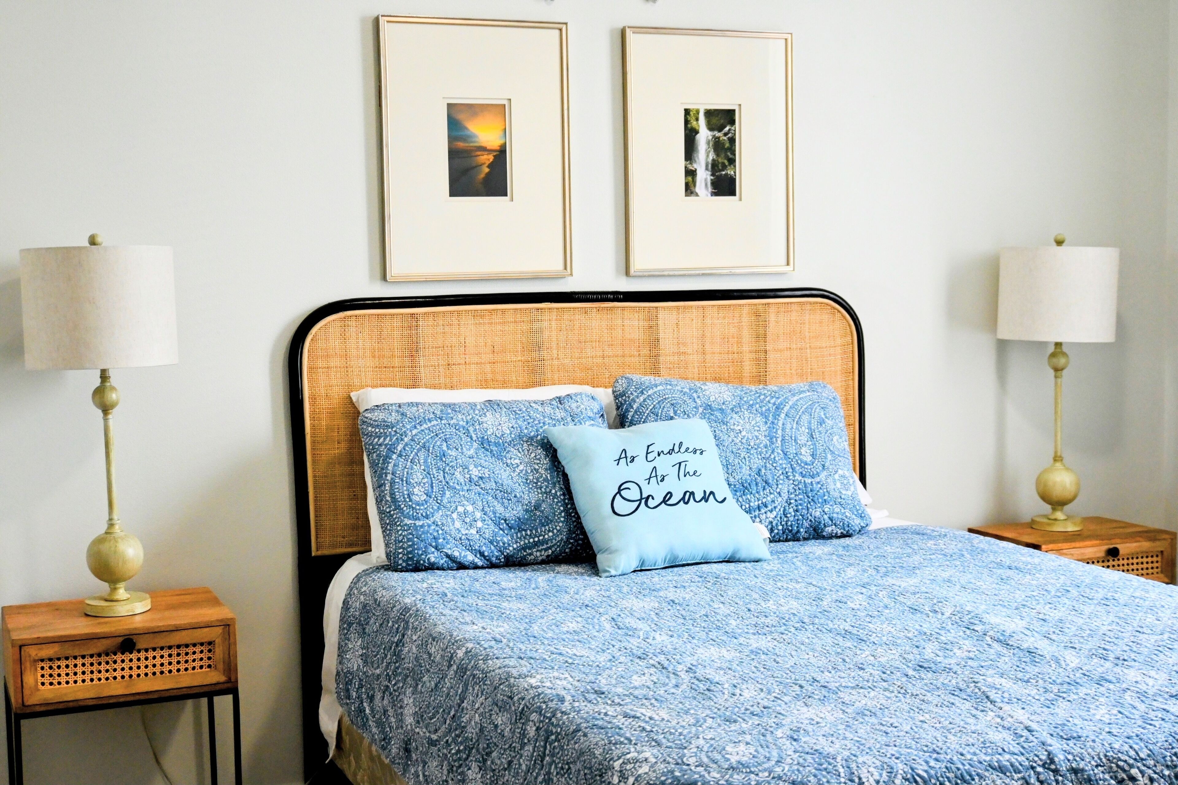 A neatly arranged bedroom with a bed, two framed pictures on the wall, and two bedside lamps.