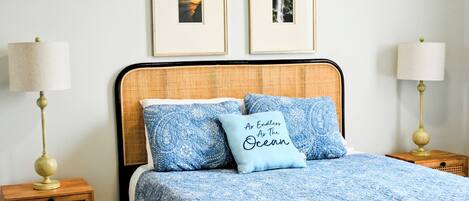 A neatly arranged bedroom with a bed, two framed pictures on the wall, and two bedside lamps.