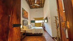 A bedroom with a bed, a nightstand, a wooden door, and a ceiling fan.