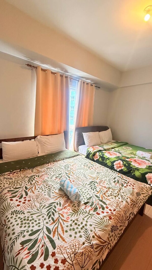 Un dormitorio con dos camas, una ventana con cortinas y una puerta a la vista.