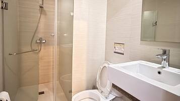 A modern bathroom with a glass-enclosed shower, a white toilet, and a large sink with a mirror above it.