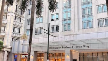 A hotel with a modern facade, large windows, and palm trees in front.
