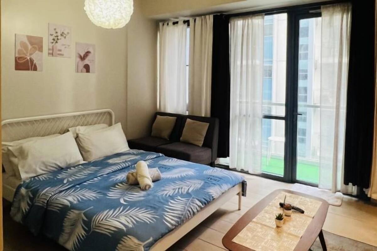 Un dormitorio con cama, sofá, una mesita de centro y vistas al exterior.