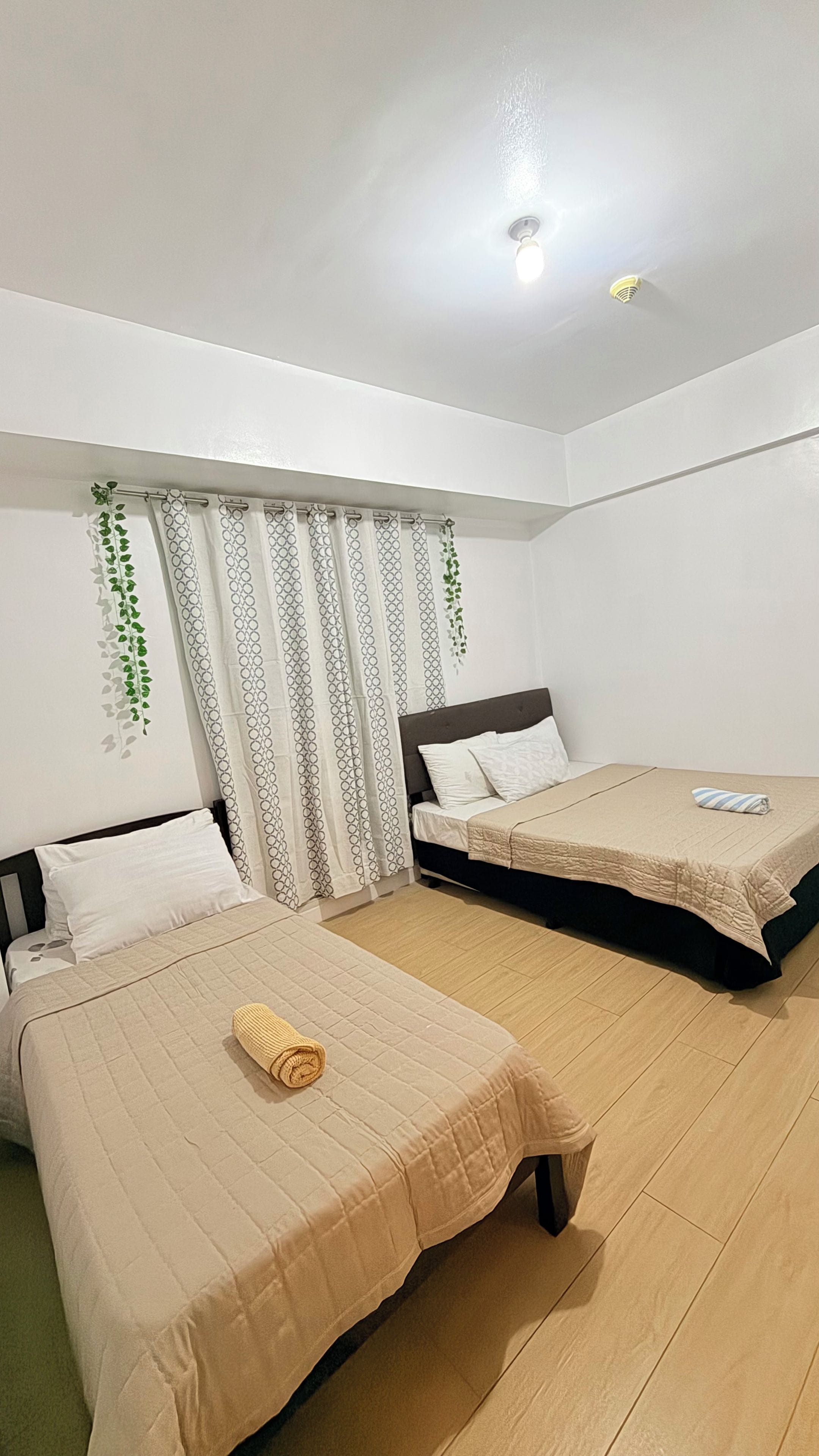 Une chambre d’hôtel avec deux lits, un plancher en bois et un luminaire au plafond.