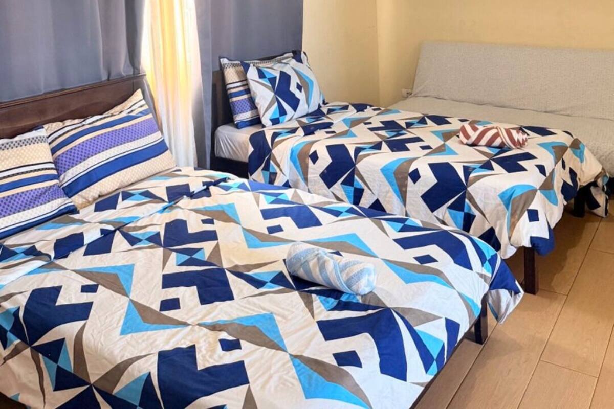 Un dormitorio con dos camas, una ventana con cortinas y una pared con tres cuadros enmarcados.