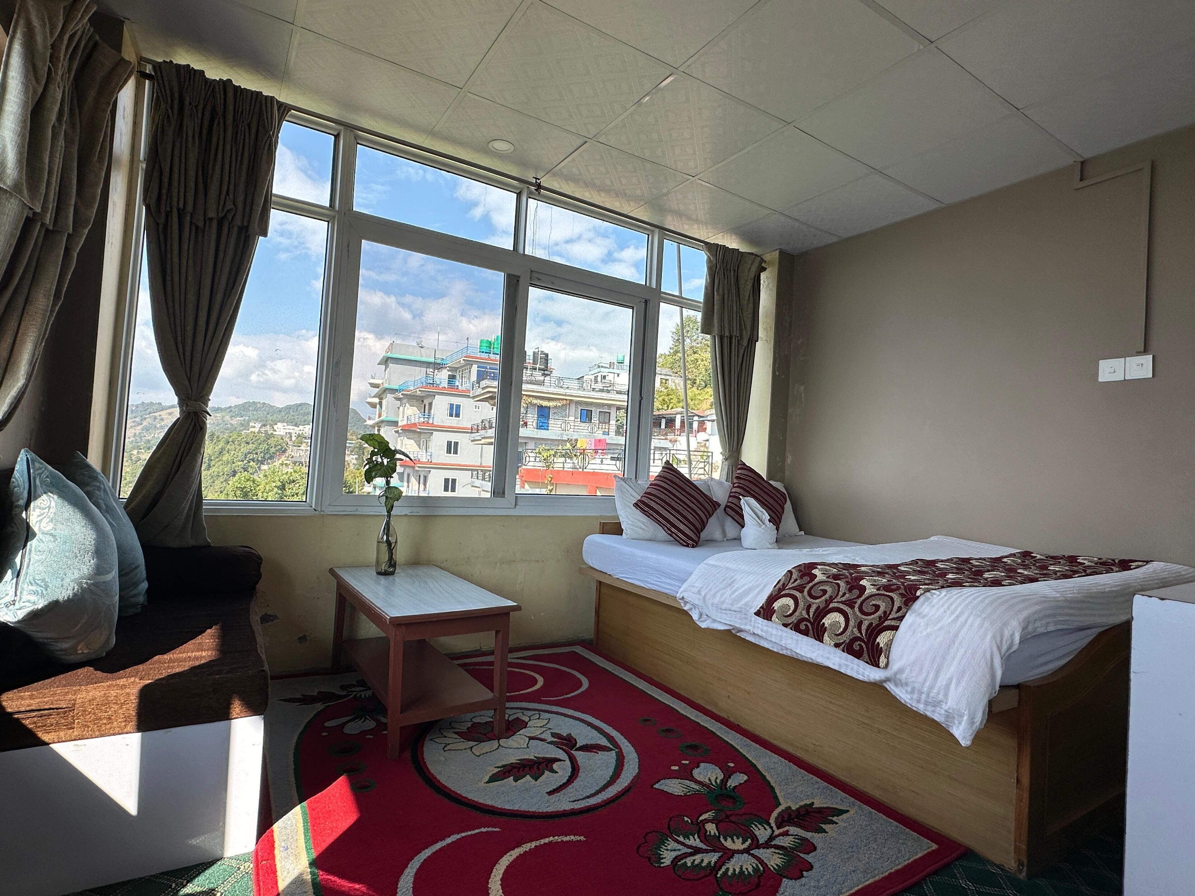 Quarto com uma cama, uma mesinha e uma janela com cortinas.