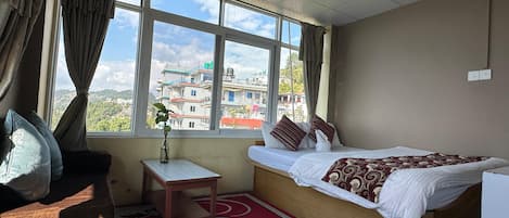 Quarto com uma cama, uma mesinha e uma janela com cortinas.
