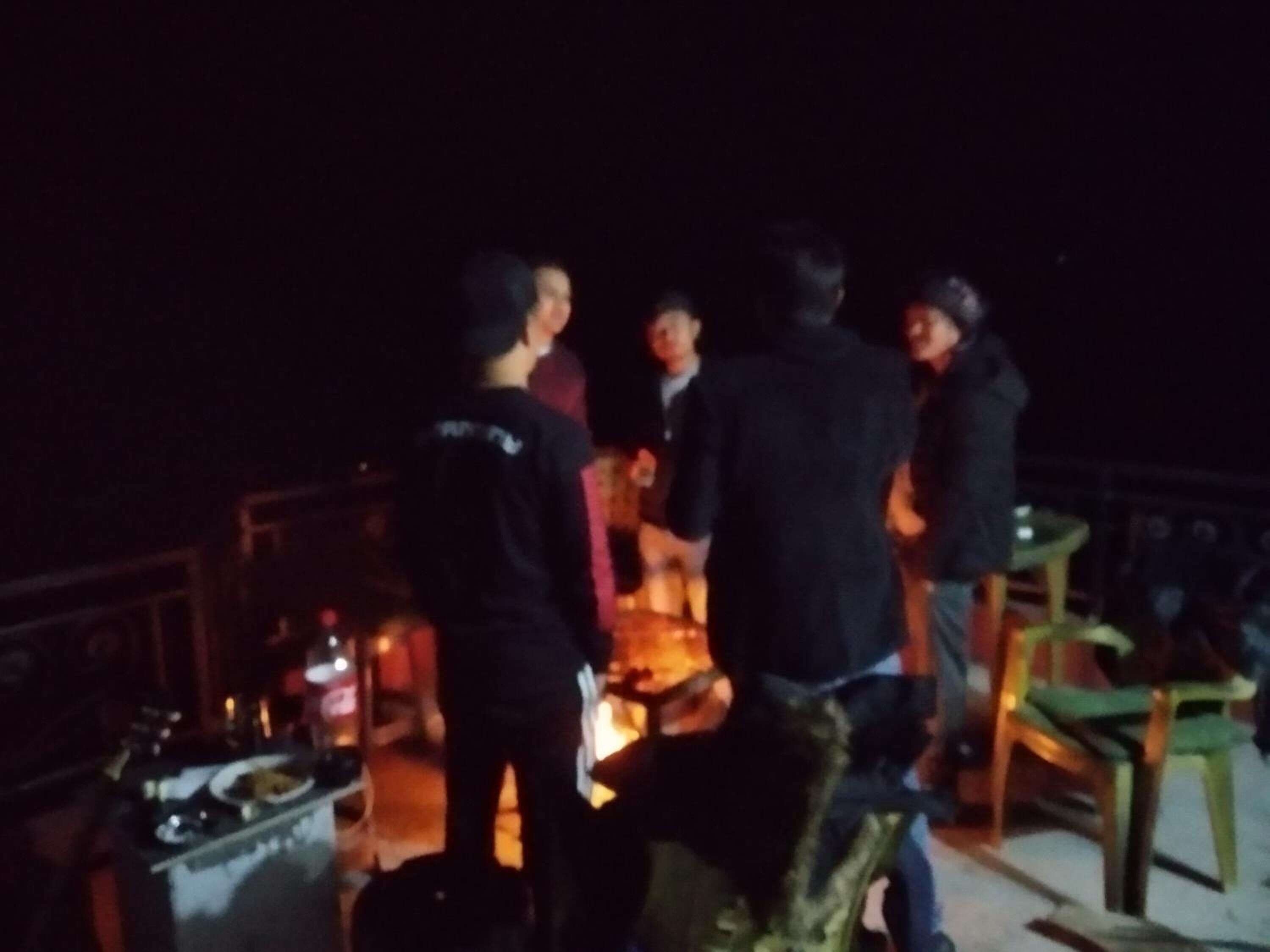 A group of people gathered around a table with food and drinks, possibly at an outdoor event or gathering.