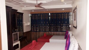 A hotel room with two beds, a television, and a ceiling fan. - Viva Guest House (Panaji)