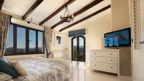 Une chambre à coucher avec un grand lit, une télévision, une commode et une vue sur l’extérieur.