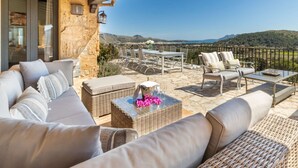 Une terrasse avec mobilier d’extérieur, un mur en pierre et une vue sur le paysage.