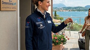 Eine Person steht vor einem Hotel, ein Schild mit der Aufschrift 'Desenzano Loft APARTMENT GARDEN'.