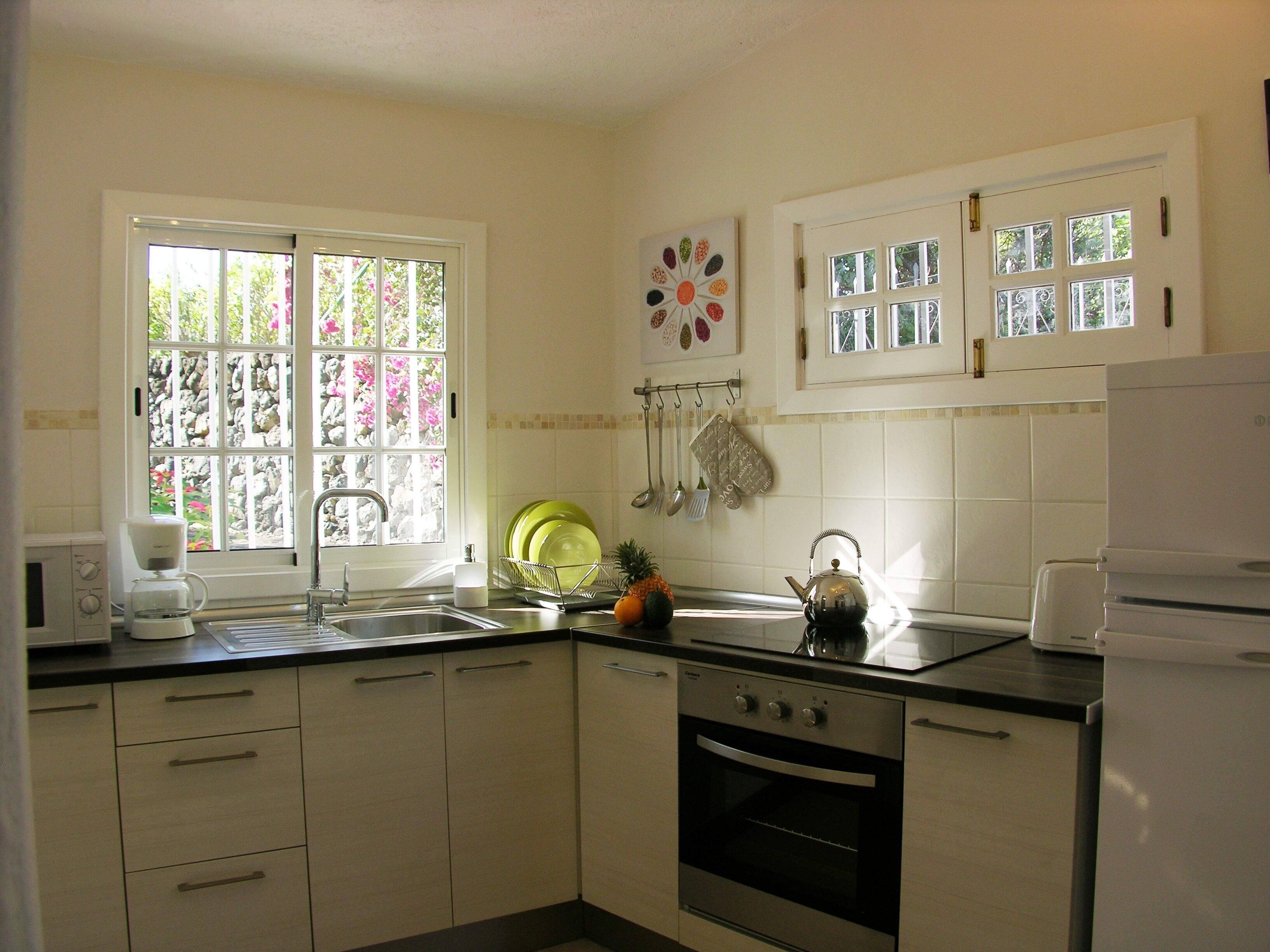 A kitchen with a built-in oven, a coffee maker, and a window with a view of greenery.