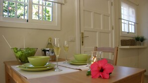 Een eettafel met groene borden, glazen en een fles, in een kamer met ramen en een deur.