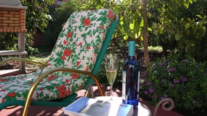 Een tuin stoel met een bloemenpatroon, een fles wijn en een glas wijn op een tafel.