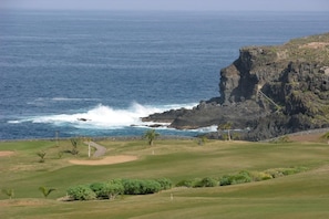 A golf course with a view of the ocean and a rocky cliff.