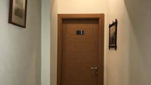 A hallway with a wooden door marked with the number 203, a framed picture on the left wall, and another framed picture on the right wall. - Historial Hotel (Istanbul)