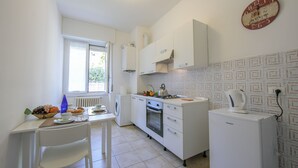 A compact kitchen with white cabinetry, a built-in oven, a coffee machine, and a window providing natural light. - Casa Al Caprifoglio - Ispra Apartment 600m From Beach, Ispra, Italy (Ispra)