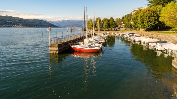 A marina with boats docked, a pier, and a view of mountains in the background. - Casa Al Caprifoglio - Ispra Apartment 600m From Beach, Ispra, Italy (Ispra)