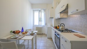 A compact kitchen with a dining table, a refrigerator, a stove, and a window providing natural light. - Casa Al Caprifoglio - Ispra Apartment 600m From Beach, Ispra, Italy (Ispra)