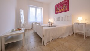 A bedroom with a bed, a bedside table, a desk, a window, and a radiator. - Casa Al Caprifoglio - Ispra Apartment 600m From Beach, Ispra, Italy (Ispra)