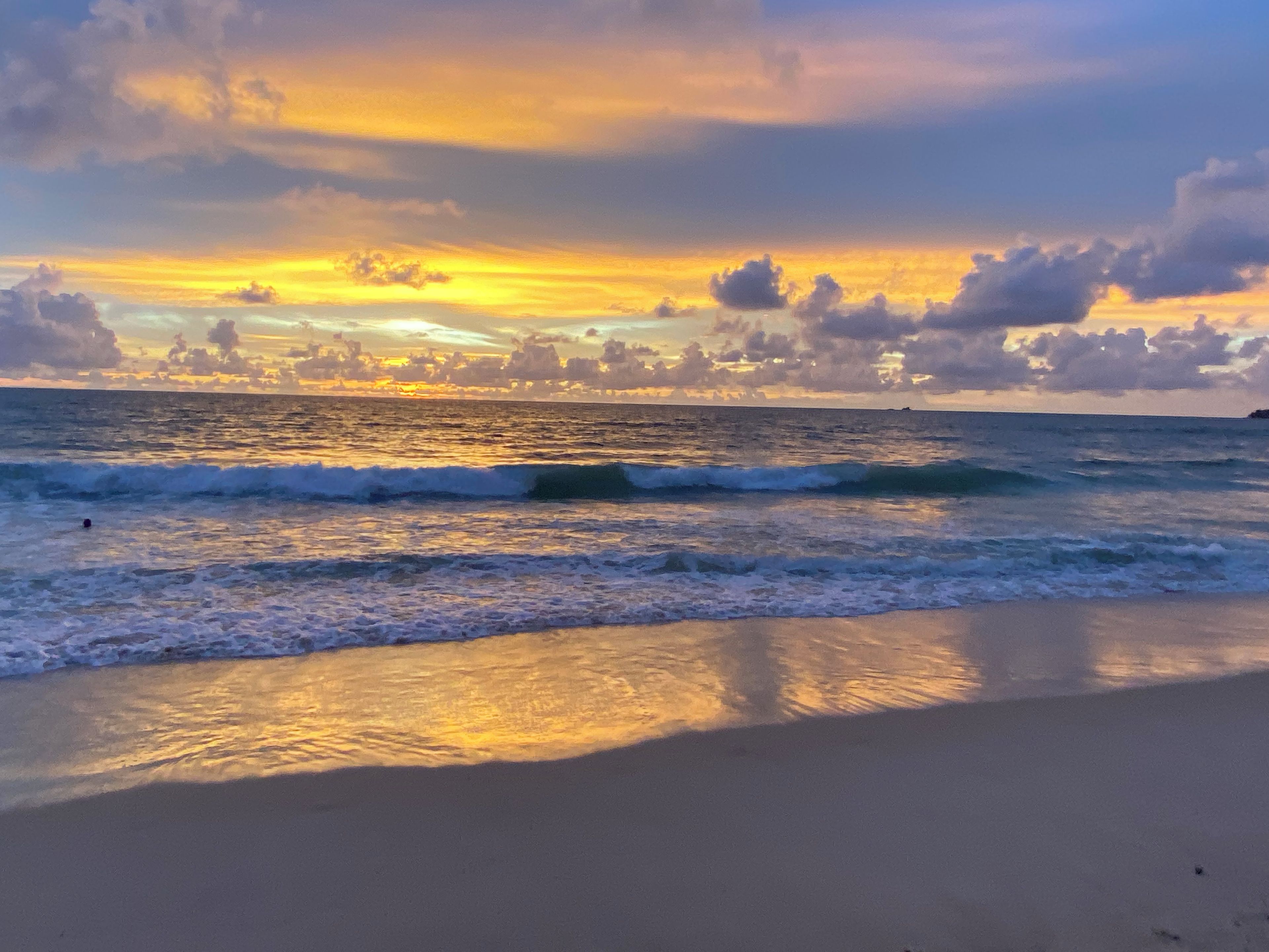A beach with waves and a sunset.