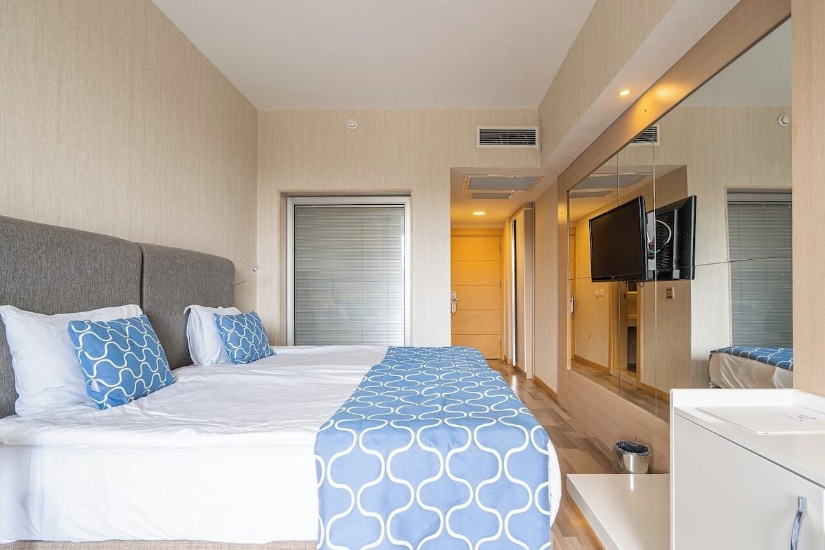 A hotel room with a bed, bedside table, and a TV mounted on the wall.