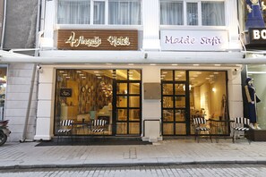 Un hotel llamado 'Angel's Hotel' con una fachada moderna, grandes ventanales de vidrio y un maniquí en la vitrina.