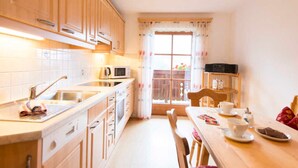 Une cuisine compacte dotée de meubles en bois, d’un four à micro-ondes, d’un évier et d’un coin repas avec une table et des chaises.