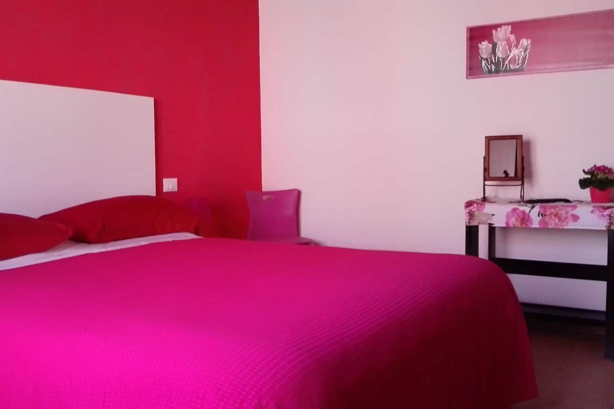 A room with a bed, a desk, and a mirror.