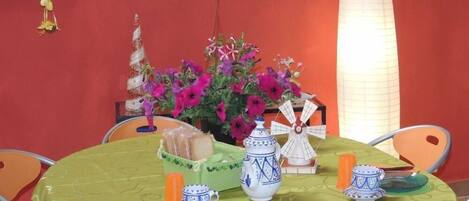 A table set with a green tablecloth, a vase with purple flowers, a decorative windmill, and various ceramic items.