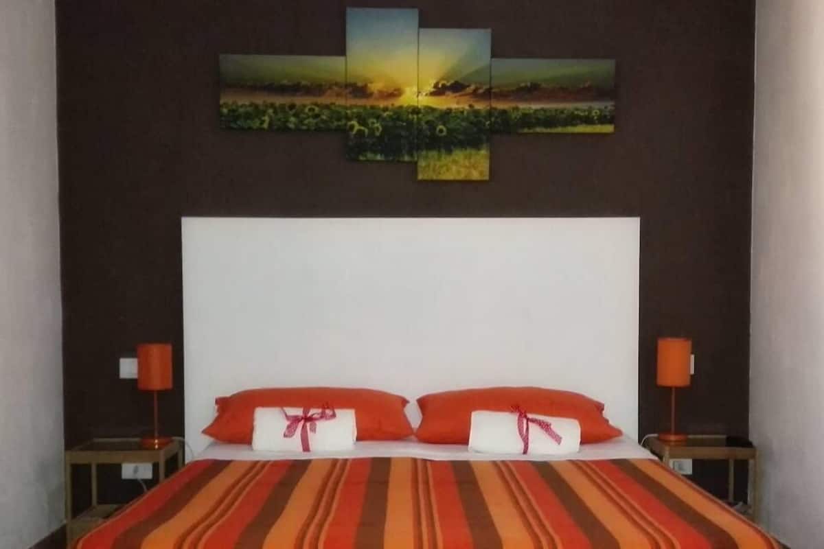 A hotel room with a large bed, two nightstands, and a wall-mounted painting.