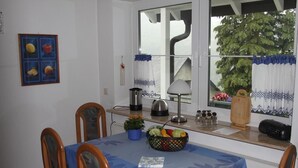 A dining area with a table set for four, a kettle, a lamp, a fruit basket, and a radio on the counter. - Ferienwohnung van Balkom (Schmallenberg)
