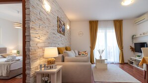 A modern living room with a stone wall, a sofa, a coffee table, and a TV.