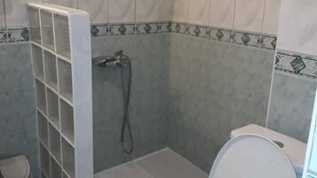 A bathroom with a shower, toilet, and a hand dryer.