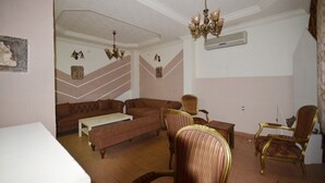 A living room with a brown sofa, a white coffee table, and a chandelier. - Ankara Antik Otel (Ankara)